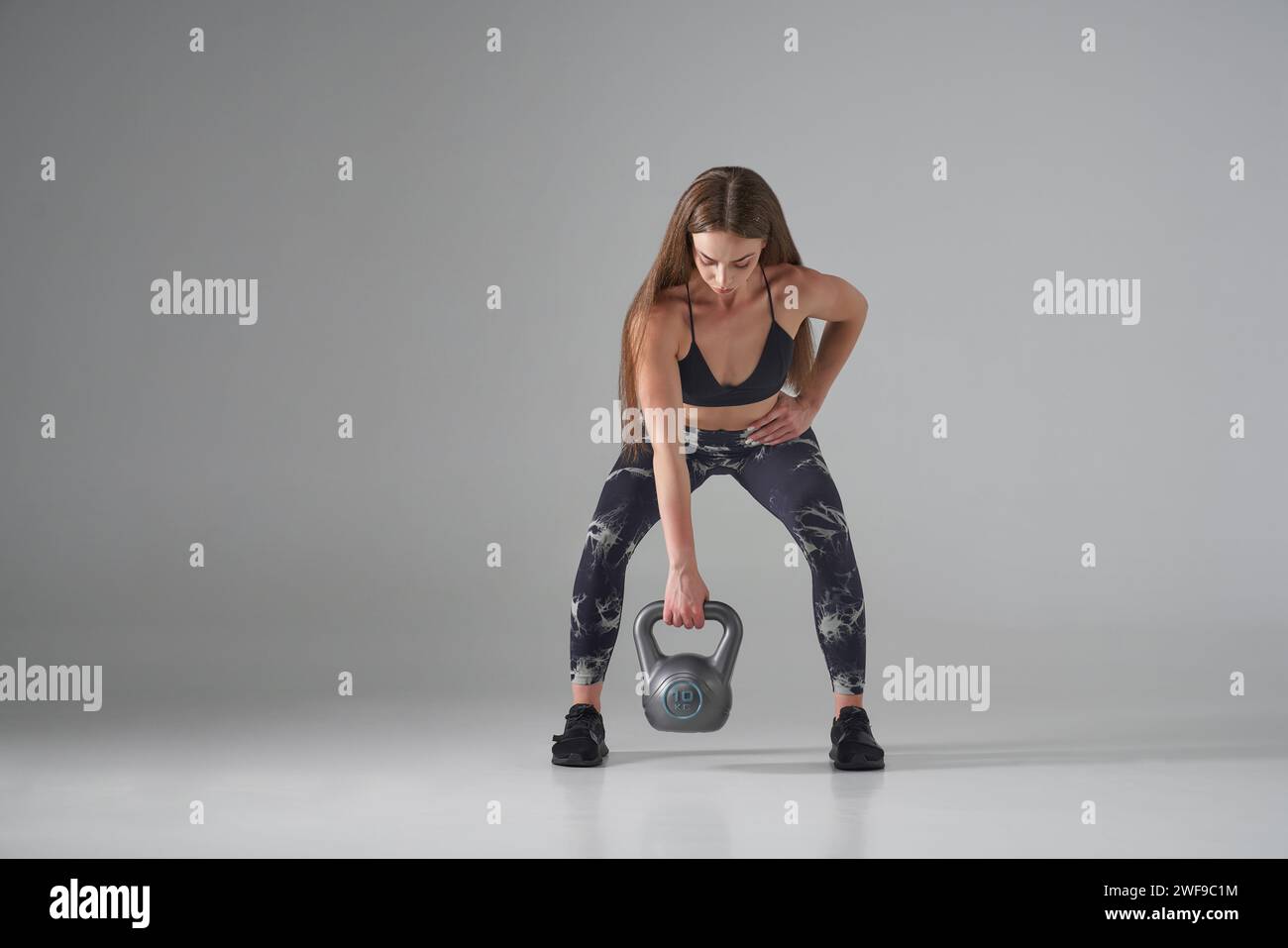 Fit femme focalisée soulevant la cloche grise de la bouilloire, l'exercice en studio. Vue de face de l'athlète féminine caucasienne utilisant un équipement de musculation, entraînement, isolé sur Banque D'Images Fit femme focalisée soulevant la cloche grise de la bouilloire, l'exercice en studio. Vue de face de l'athlète féminine caucasienne utilisant un équipement de musculation, entraînement, isolé sur Banque D'Images