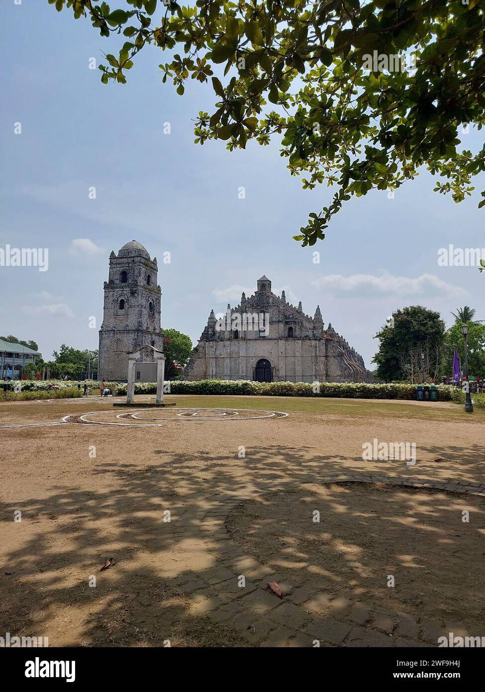 Une église de Paoay entourée d'arbres verdoyants et d'un terrain sablonneux Banque D'Images