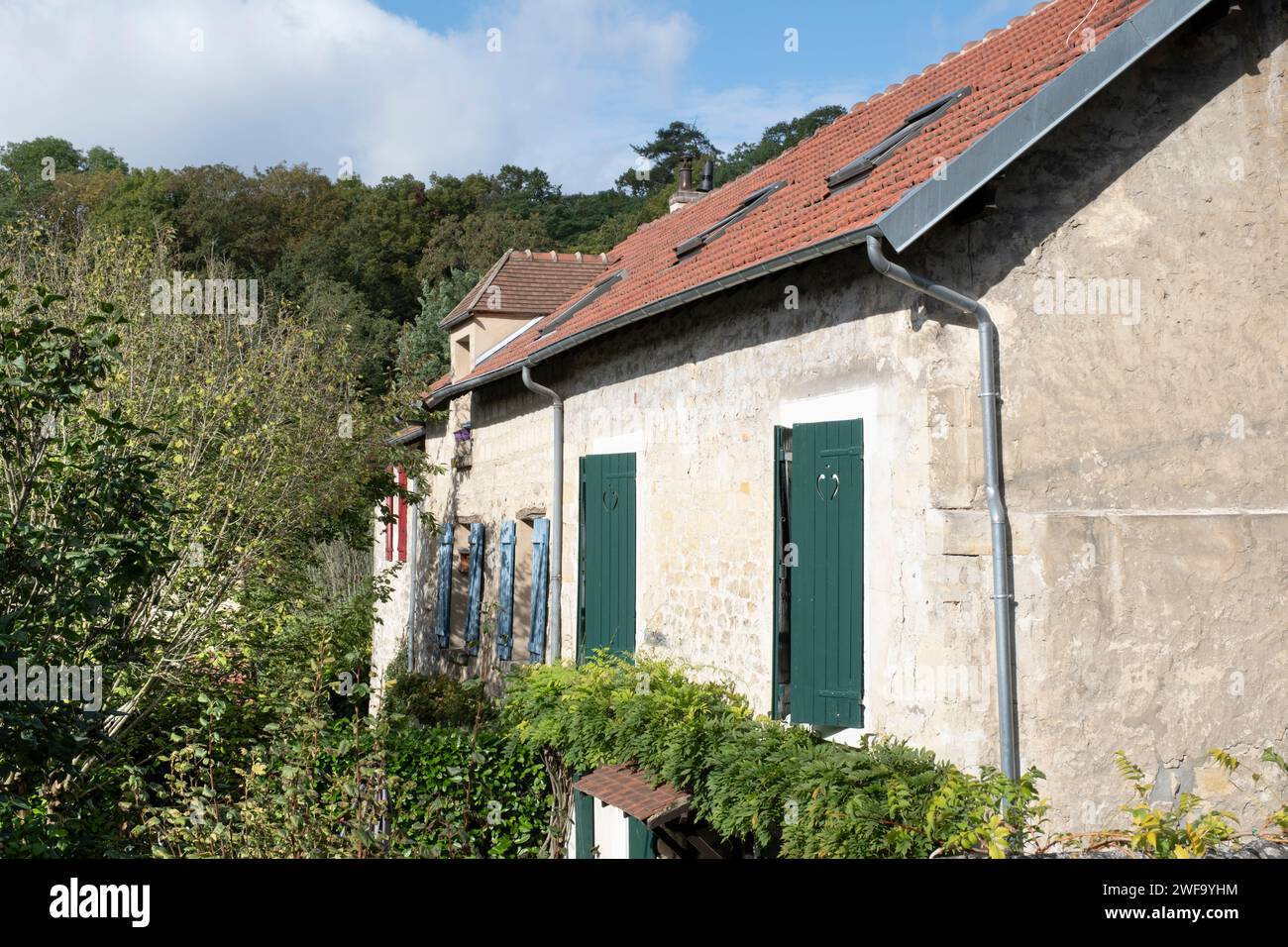 Maison à Auvers-sur Oise en France avec murs en plâtre et fenêtres aux volets de différentes couleurs, rouge, bleu et vert Banque D'Images