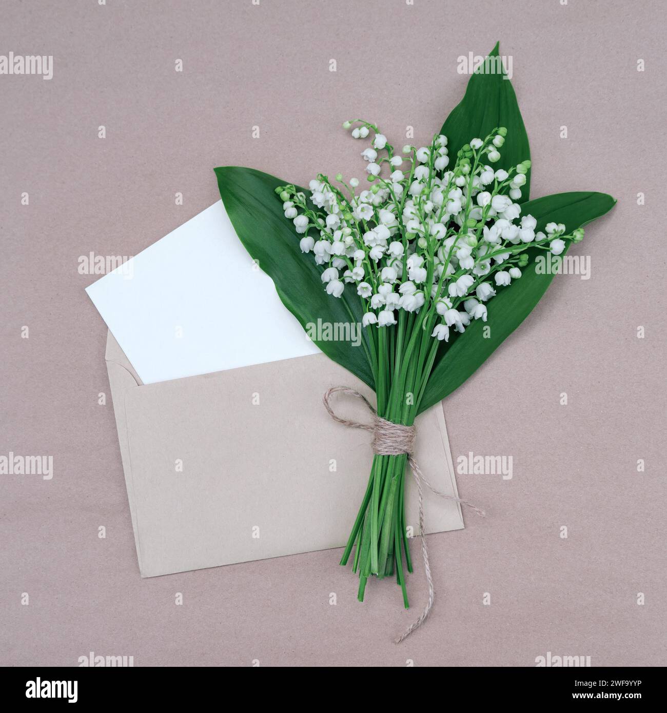 Carte de voeux élégante avec un bouquet de lys blancs de la vallée dans une enveloppe Banque D'Images