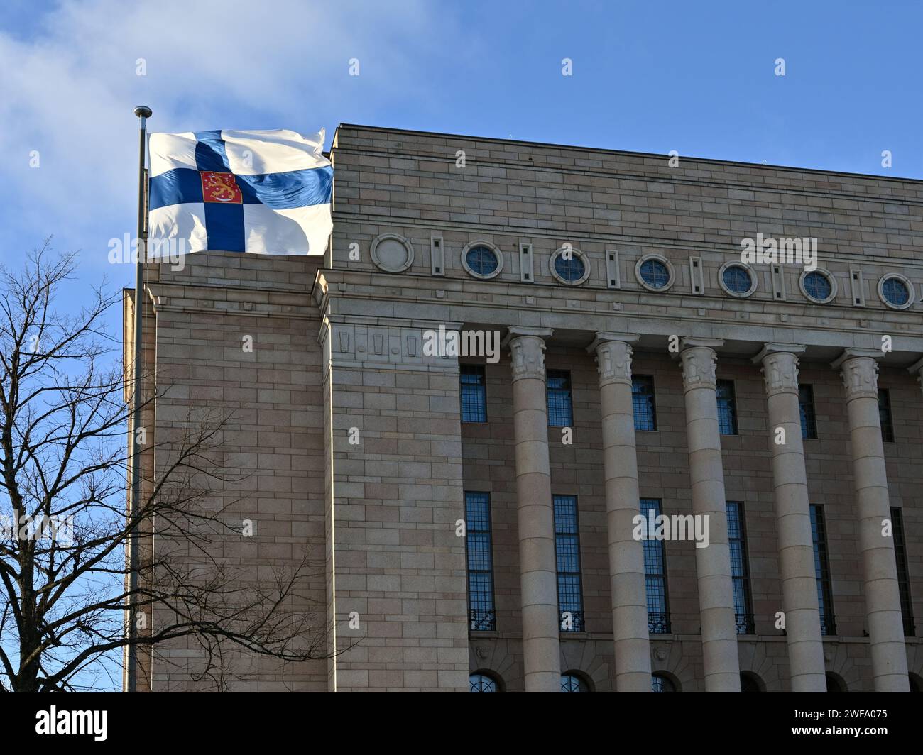 Brandissant le drapeau finlandais et le bâtiment du Parlement finlandais le jour de l'indépendance finlandaise Banque D'Images