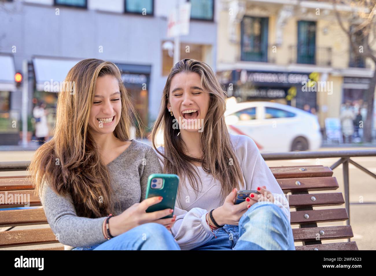 deux jeunes amis s'amusant à regarder le téléphone regarder la vidéo en ligne tenir le téléphone portable habillé dans des vêtements décontractés. Deux amies féminines s'amusent ensemble Banque D'Images