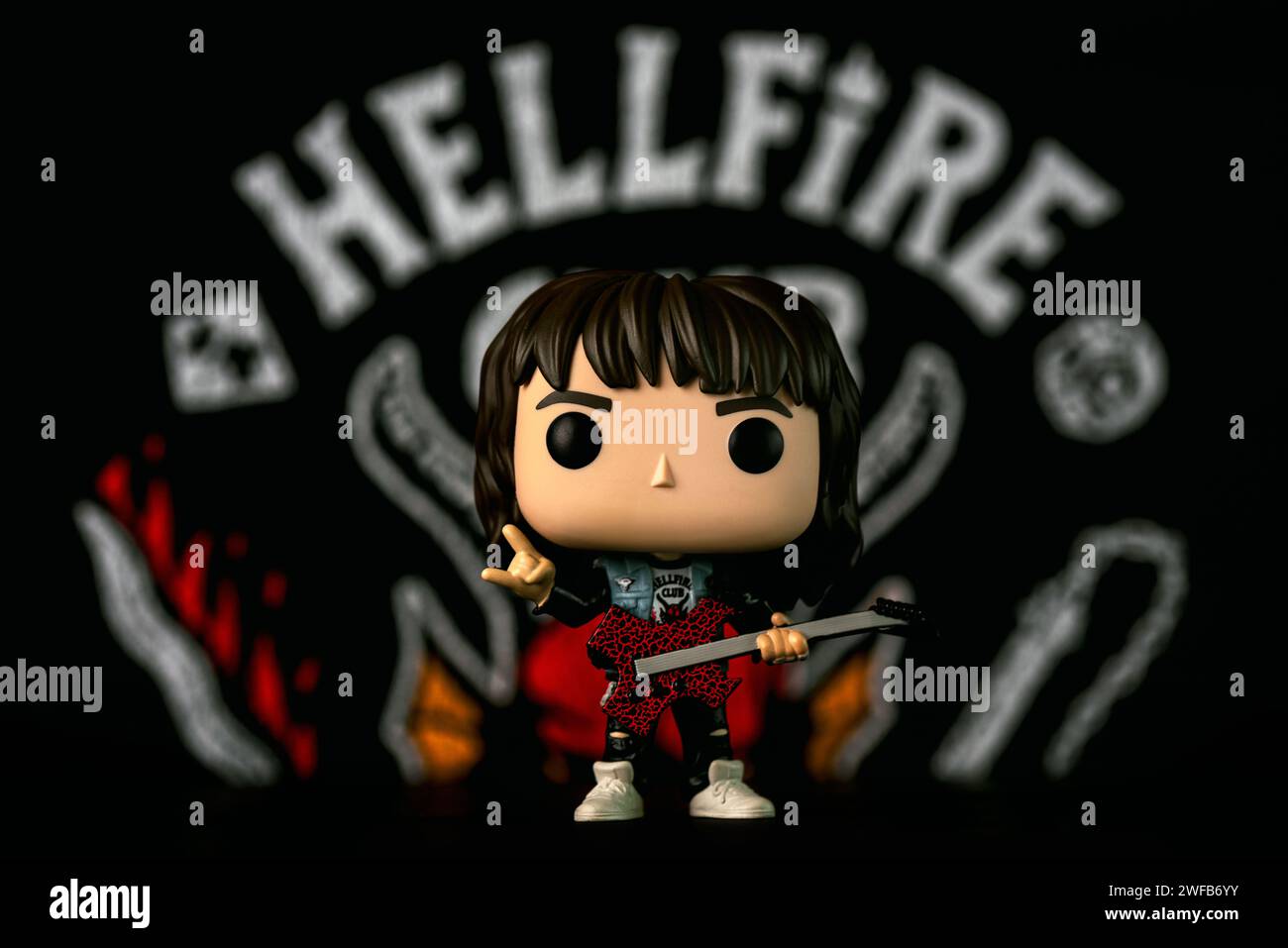 Funko figurine vinyle POP d'Eddie Munson personnage de la série télévisée Stranger Things devant l'affiche du Hellfire Club. Editorial illustratif de Funko po Banque D'Images