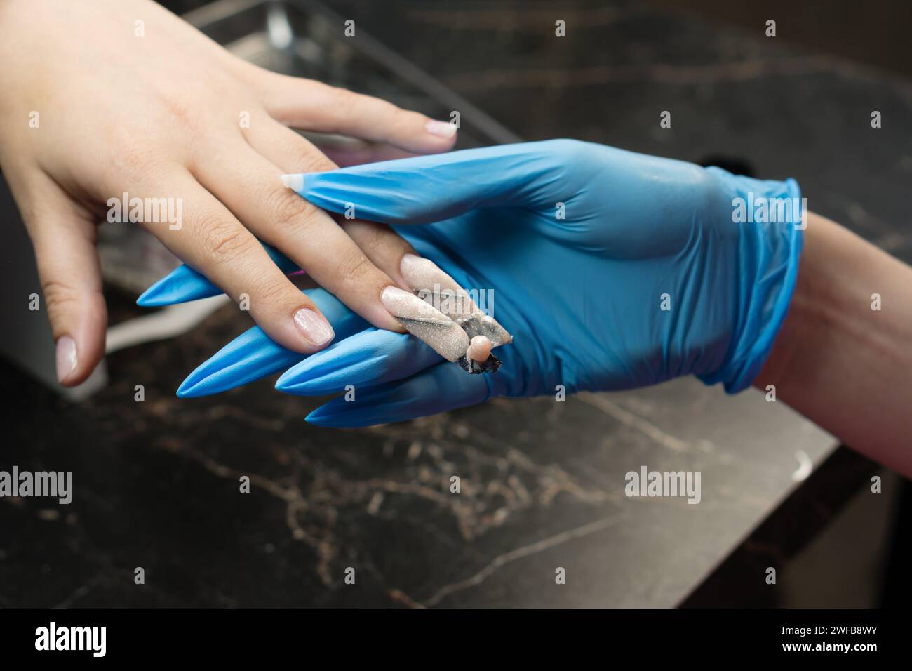Nail artist effectuant des touches finales sur une manucure d'ongle de bord. Banque D'Images