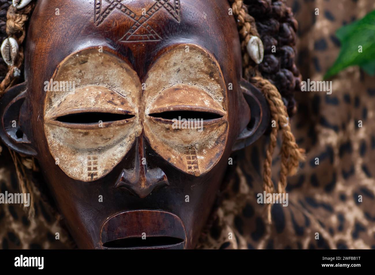 Masque africain tribal en bois de l'Ouganda, pour la protection de la famille ou personnelle, fait de bois local, cordes et coquillages comme décoration de cheveux Banque D'Images