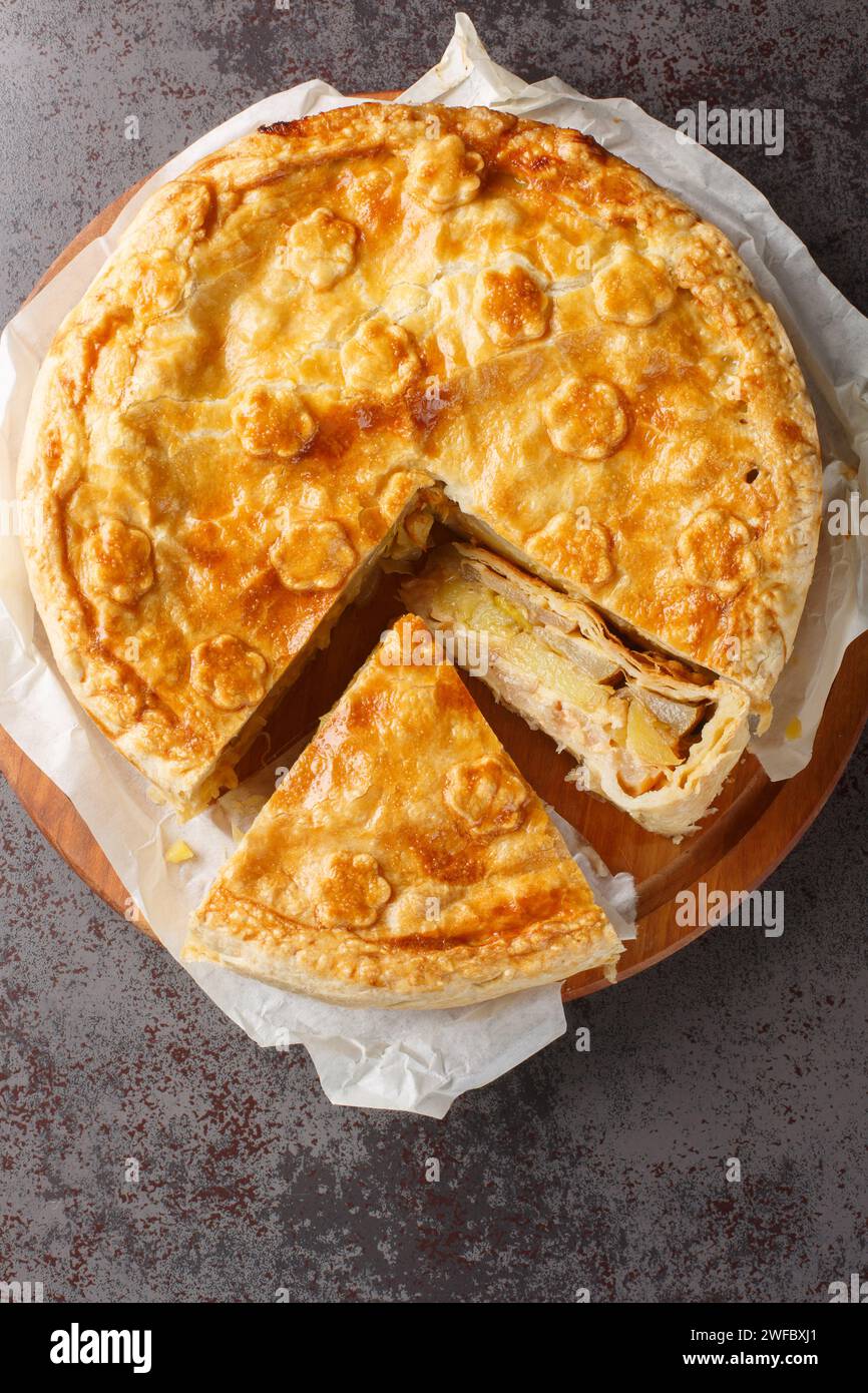 Délicieuse tarte suisse au choléra avec pomme, pomme de terre, poire, oignon et fromage en gros plan sur une planche de bois sur la table. Vue verticale de dessus Banque D'Images