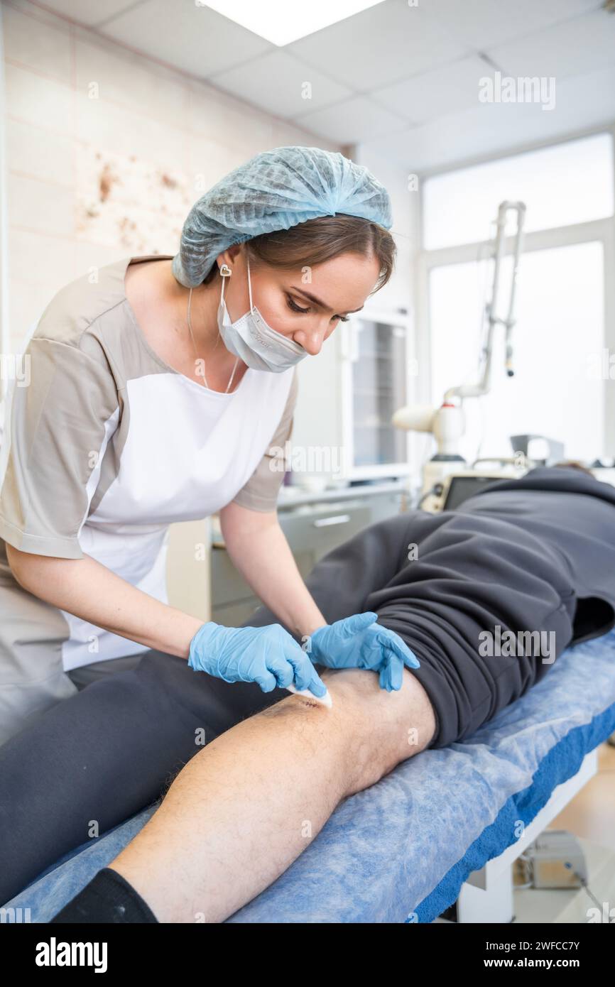 Jeune travailleur médical traitant les plaies et enlevant les points de suture Banque D'Images
