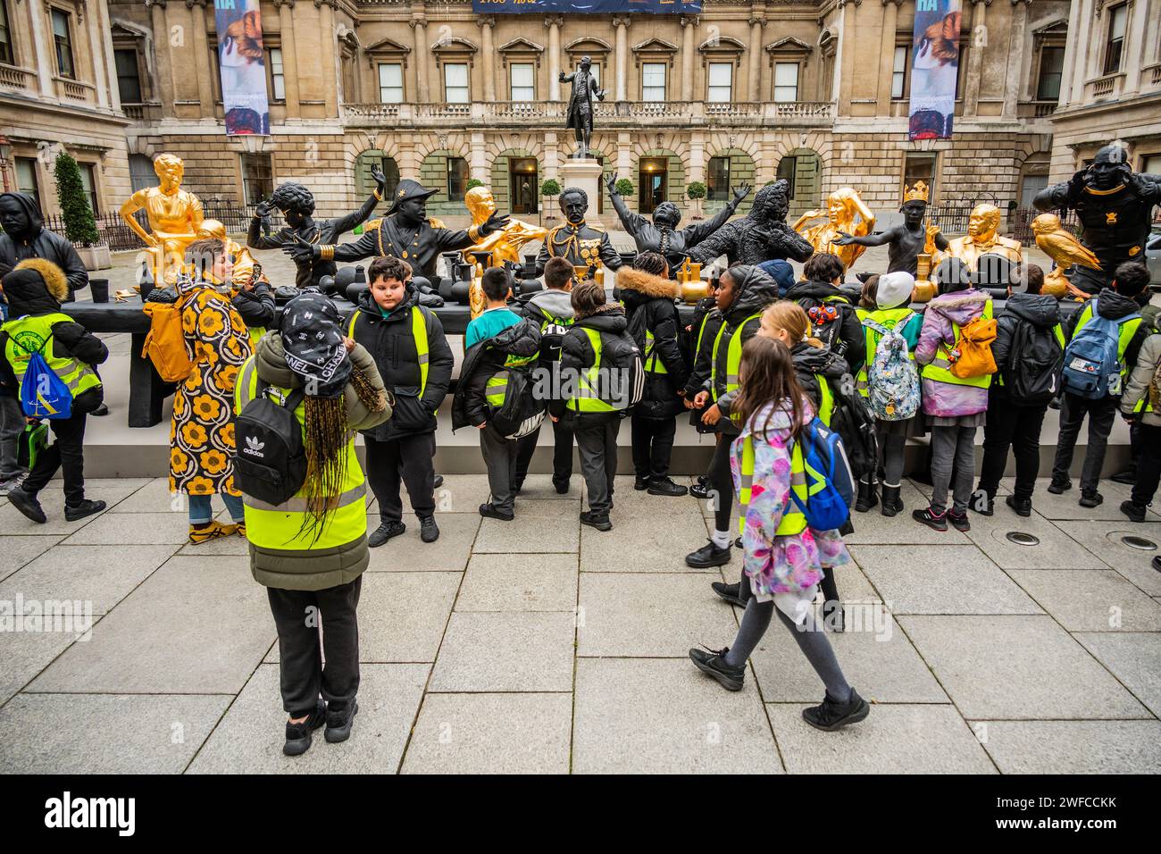 Londres, Royaume-Uni. 30 Jan 2024. Une fête scolaire de la Chapel End Junior Academy examine la nouvelle sculpture de Tavares Strachan, la première Cène, 2021-23, dans la cour Annenberg dans le cadre de la nouvelle exposition Entangled Pasts : 1768-Now : Art, Colonialism and change, à la Royal Academy of Arts La première Cène représente ce que Strachan décrit comme un rassemblement utopique qui rassemble des personnages historiquement significatifs du continent africain et de ses diasporas, accompagnés d’un tigre thylacine ou de Tasmanie et d’un portrait de l’artiste. Il comprend des portraits sculpturaux du résistant Zumbi Banque D'Images