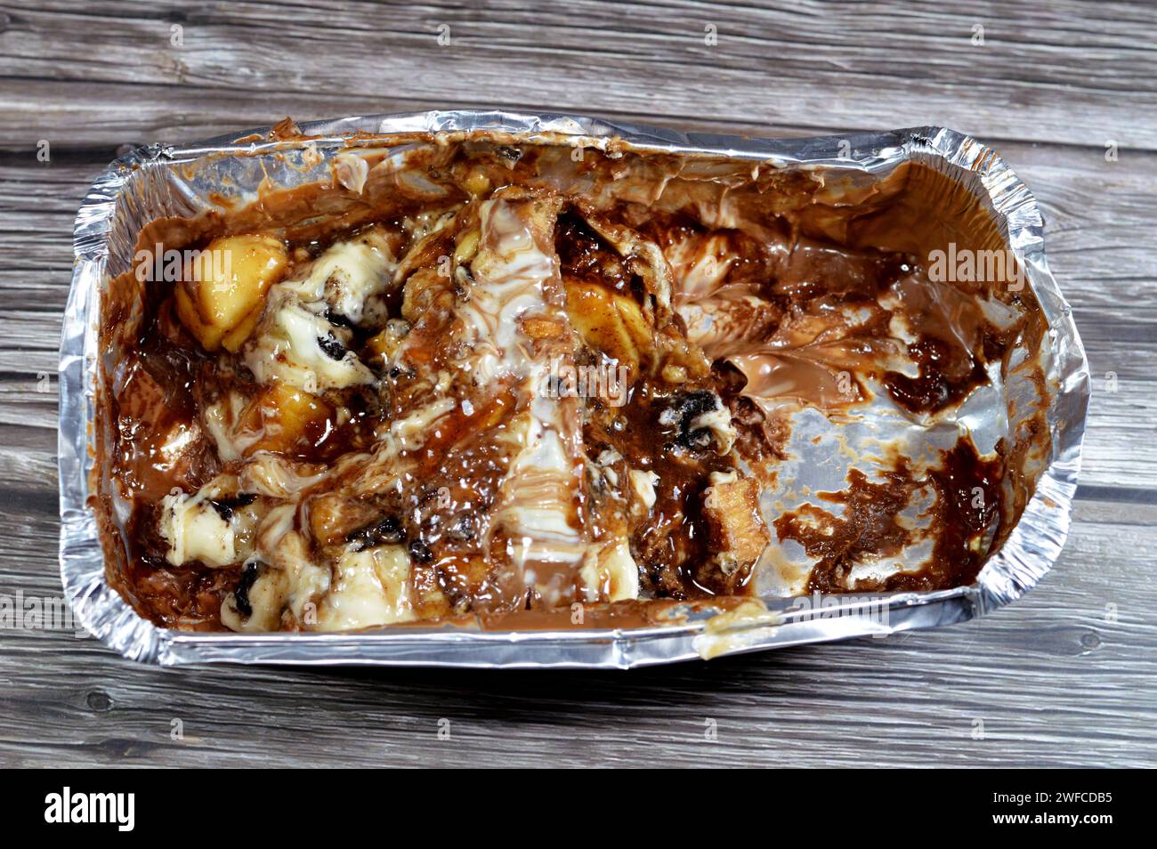 Une pâte à tarte cuite recouverte de sauce au chocolat et farcie de morceaux de chocolat, de morceaux de biscuit, de banane, de gâteau, de caramel et de chocolat noisette crea Banque D'Images