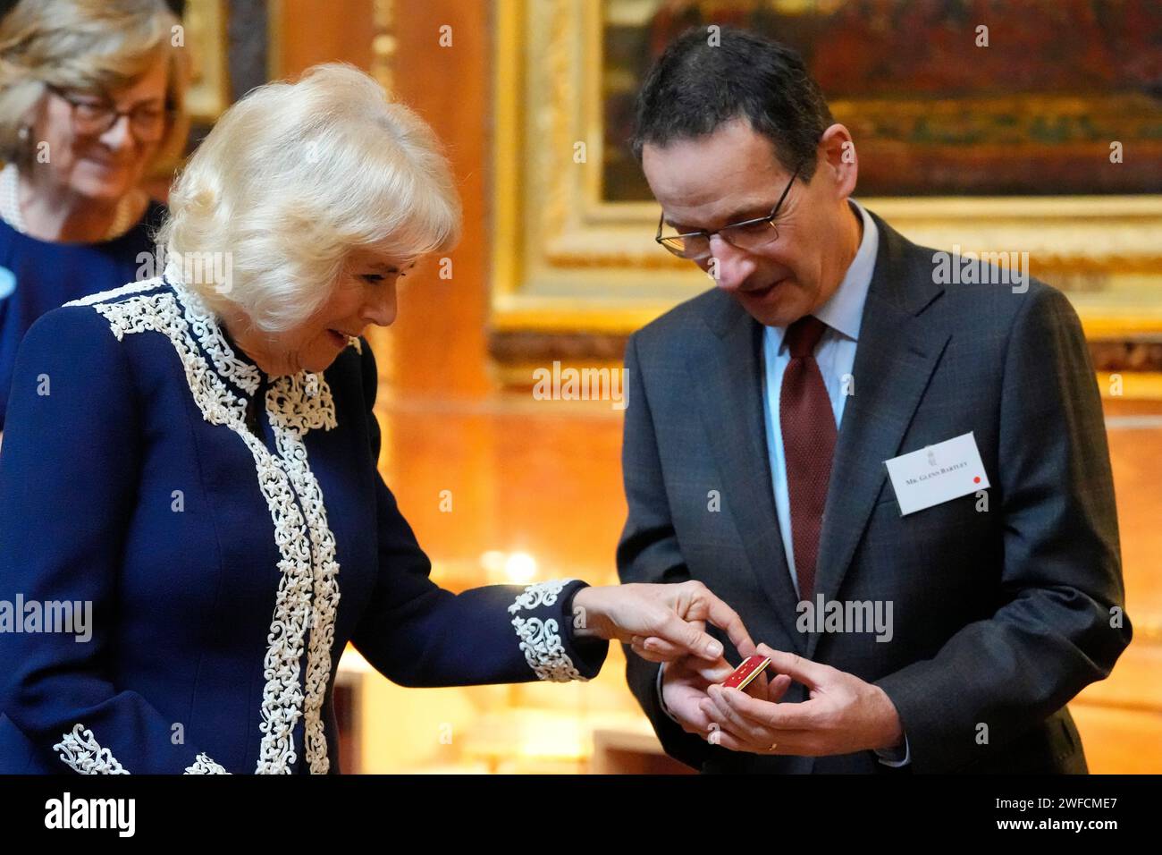 La reine Camilla reçoit un livre miniature de Glenn Bartley, chef de la Royal Bindery, lors d'une réception au château de Windsor, Berkshire, pour les auteurs, illustrateurs et classeurs qui ont participé à la nouvelle collection de la bibliothèque miniature exposée à côté de la maison de poupées de la reine Mary pour que les visiteurs puissent en profiter tout au long de l'année 2024 pour célébrer son centenaire. Date de la photo : mardi 30 janvier 2024. Banque D'Images