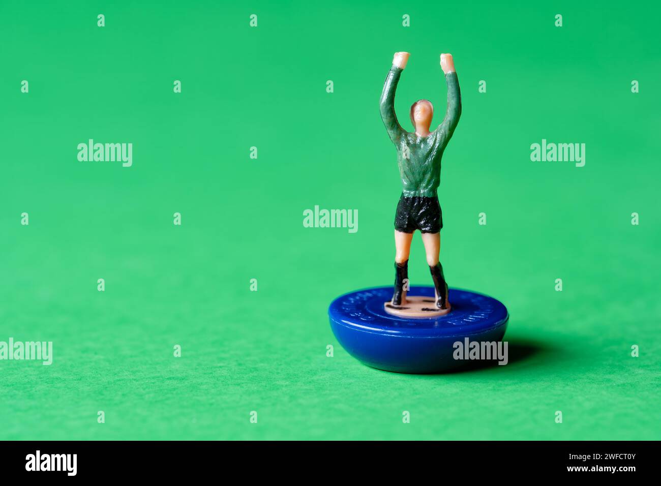 Une seule figurine de gardien de but miniature Subbuteo peinte dans une chemise verte et un short noir. Subbuteo est un jeu de football de table populaire Banque D'Images