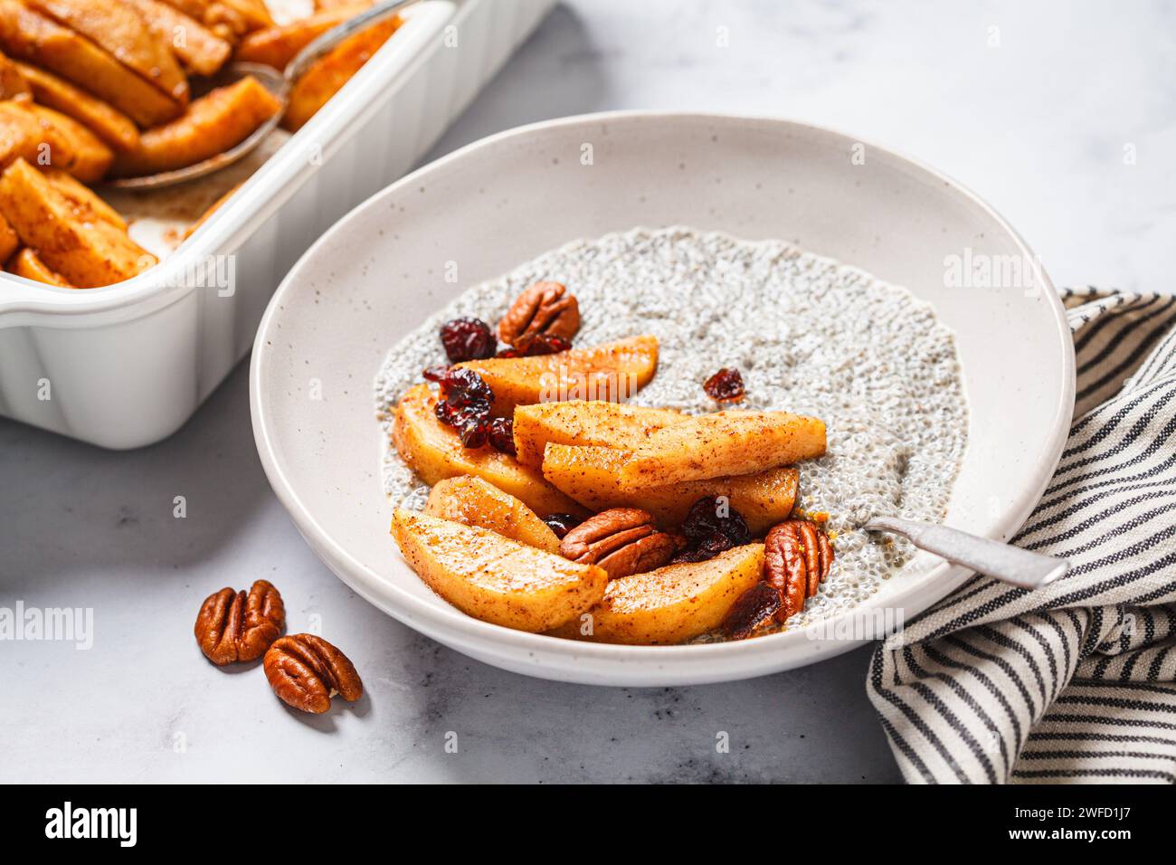 Pudding de chia avec pommes caramélisées, cannelle, noix de pécan et canneberges. Recette de petit déjeuner végétalien hiver. Banque D'Images