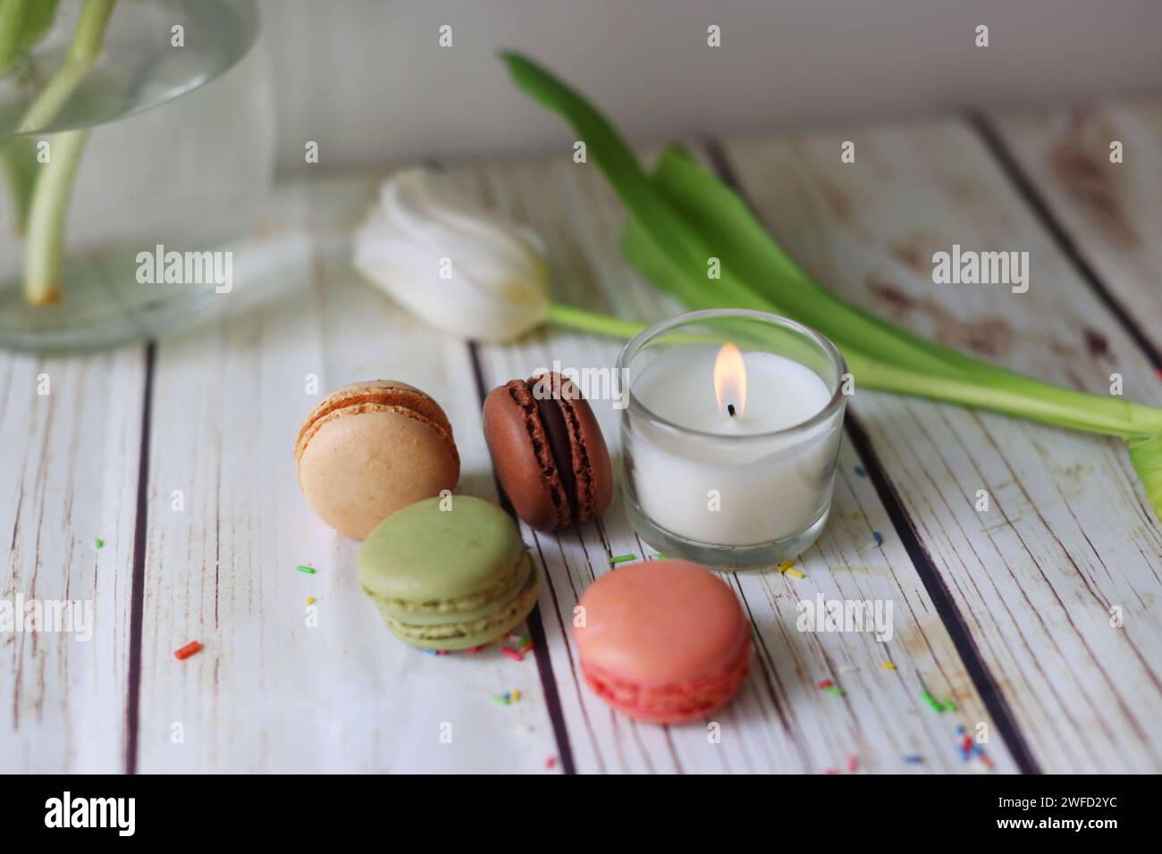 Nature morte romantique avec une bougie, des macarons et des tulipes Banque D'Images