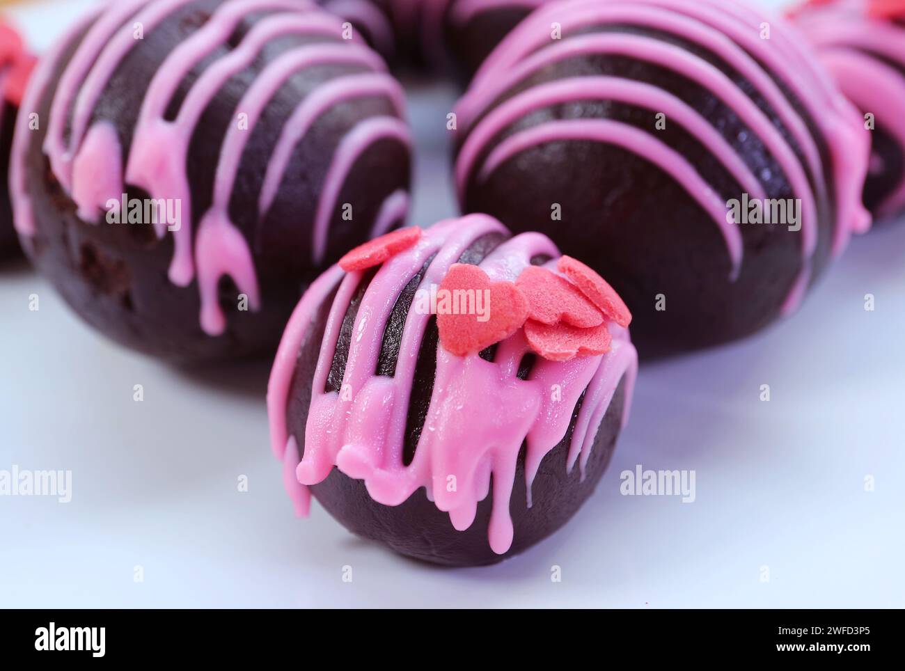 Gros plan de succulents gâteaux au chocolat enrobés de glaçage royal aux fraises en forme de cœur Banque D'Images