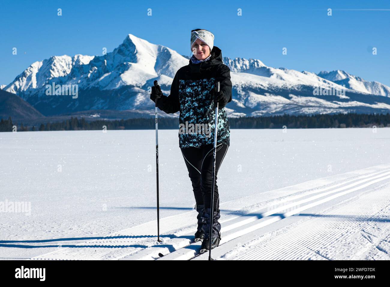 Jeune femme ski de fond sur un pré enneigé avec vue sur les Hautes Tatras-Kriváň. Banque D'Images