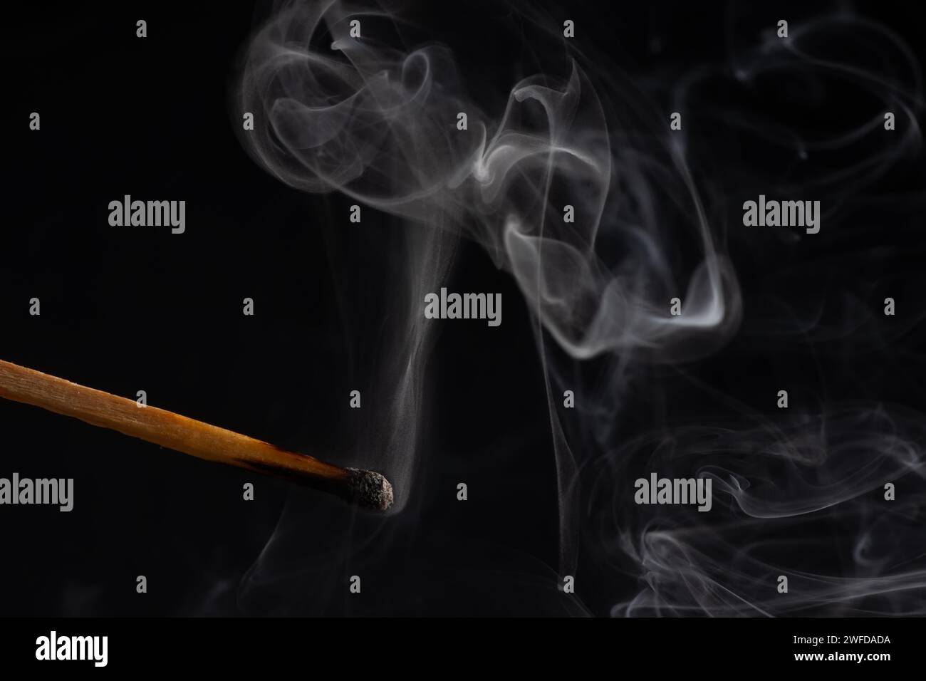 Fumée d'une allumette qui vient d'être éteinte, isolée sur fond noir. Banque D'Images