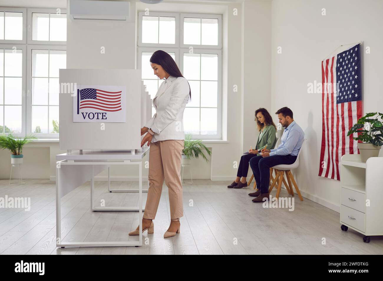 Jeune femme votante américaine debout au centre de vote dans la cabine de vote faisant un choix le jour de l'élection. Banque D'Images