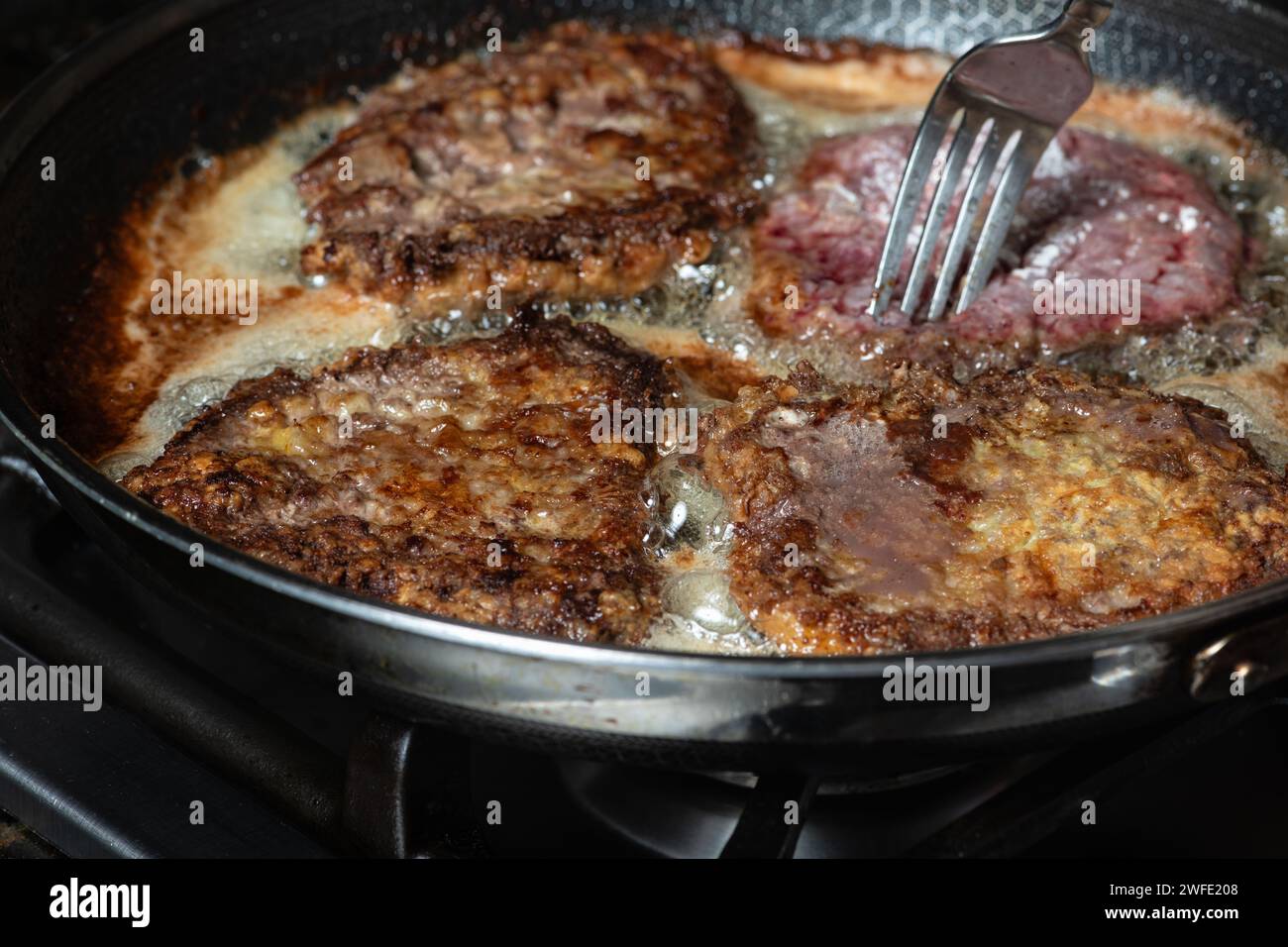 Schnitzel frit dans une poêle sur la table de cuisson à gaz. Concept de cuisine maison. Banque D'Images