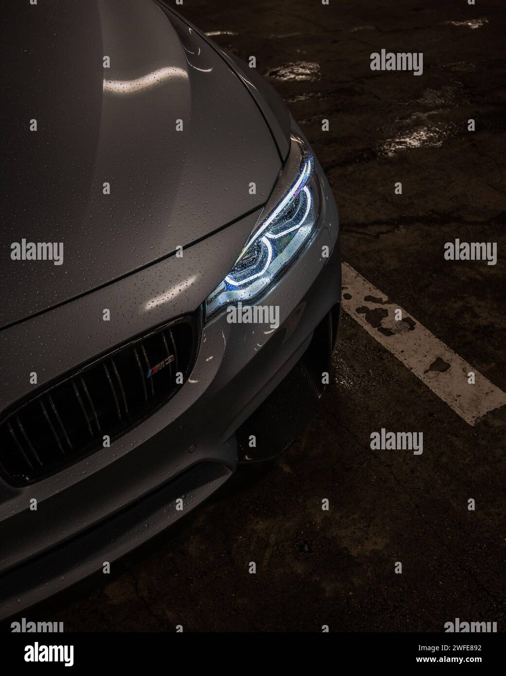 Gros plan d'une élégante voiture AMG avec des gouttes de pluie stationnées dans un éclairage tamisé Banque D'Images