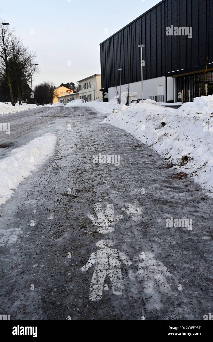 Trottoir couvert de glace avec un panneau de chemin piétonnier parsemé de copeaux de granit Banque D'Images