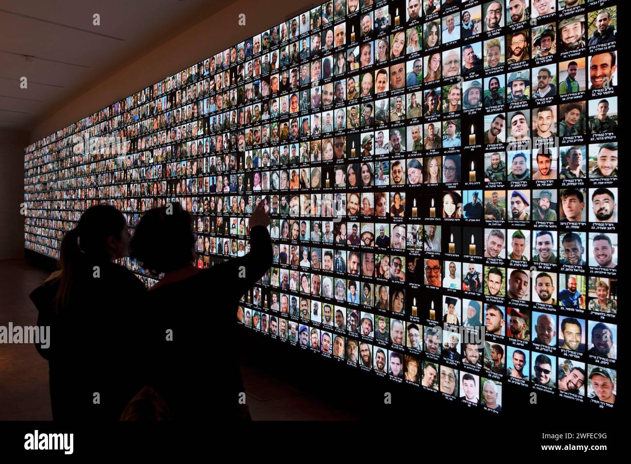 FILE - Visitors look at photos of Israeli people who were killed during Hamas militants attack on Oct. 7 and those who died during the Israel-Hamas war in the Gaza Strip, displayed on a giant screen at the National Library in Jerusalem, Israel, Sunday, Jan. 28, 2024. Netanyahu is under mounting pressure from families of the hostages and the wider public to reach a deal with Hamas to bring the captives home. Many Israelis fear time is running out. (AP Photo/Leo Correa, File) Banque D'Images