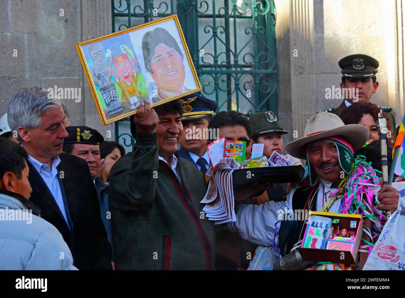 La Paz, BOLIVIE ; 24 janvier 2015. Le président bolivien Evo Morales tenant une photo de lui-même lors d’un événement marquant le début du festival Alasitas à la Paz. L'image était un cadeau de l'homme à droite qui est habillé en Ekeko, un dieu aymara d'abondance associé au festival. Au festival, les gens achètent des miniatures de ce qu'ils veulent obtenir au cours de l'année et les font bénir pour que leurs souhaits deviennent réalité. Les miniatures populaires disponibles comprennent des voitures, des maisons, de l'argent, des certificats de diplôme, des valises et des passeports (pour voyager). Banque D'Images