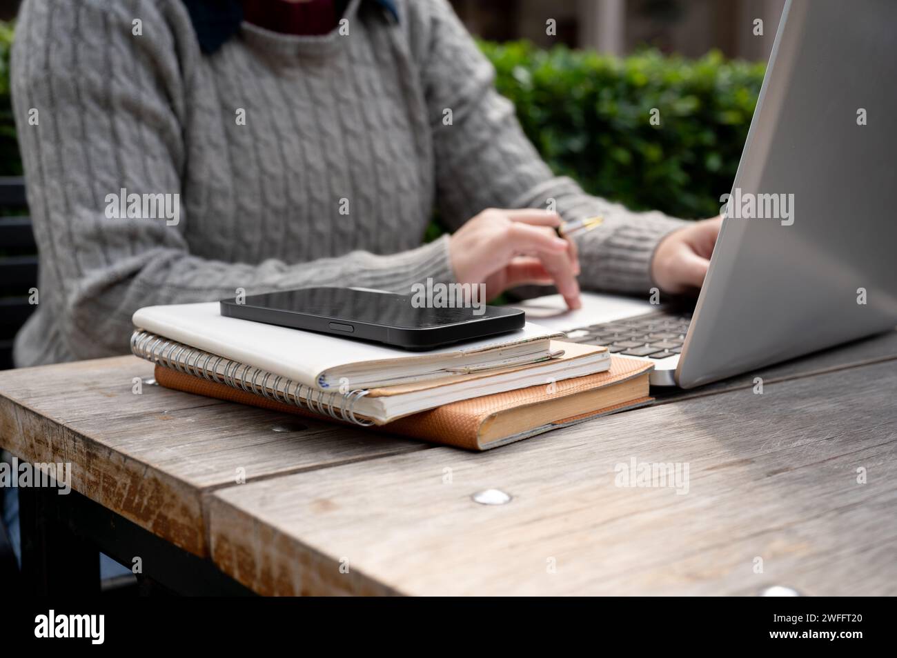 Une femme utilisant son ordinateur portable à une table à l'extérieur. travail à distance, freelance, nomade numérique, personnes et technologie sans fil Banque D'Images