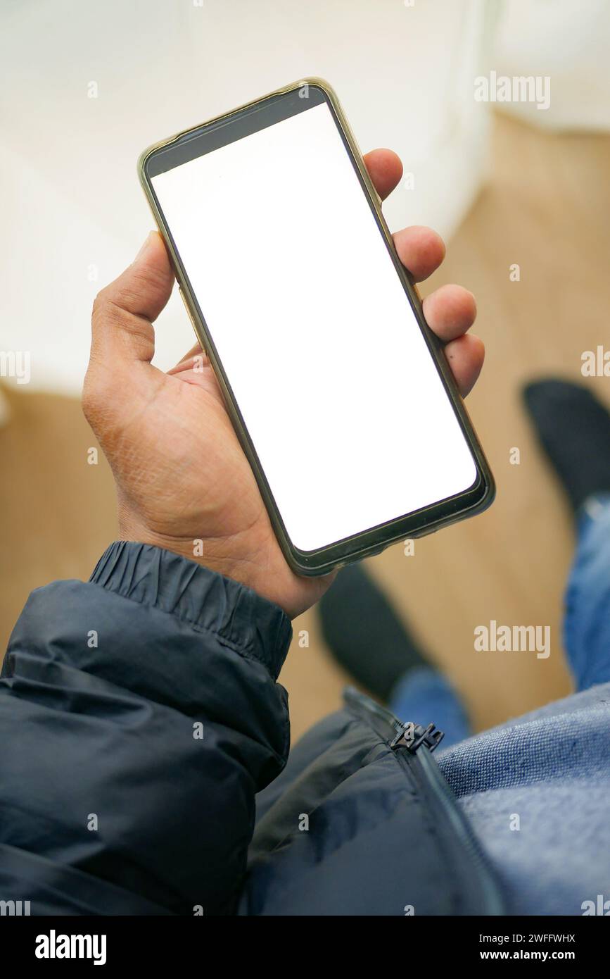 tenant le téléphone intelligent avec l'écran blanc et la décoration intérieure de la maison sur la table Banque D'Images