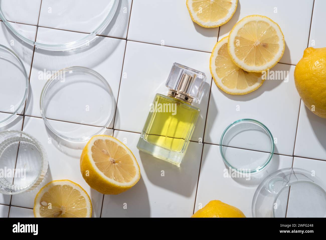 Flacon transparent en verre de parfum extrait de l'huile essentielle de citron disposé avec des boîtes de Pétri et des tranches de citron. Citron (Citrus limon) peut être utilisé i Banque D'Images