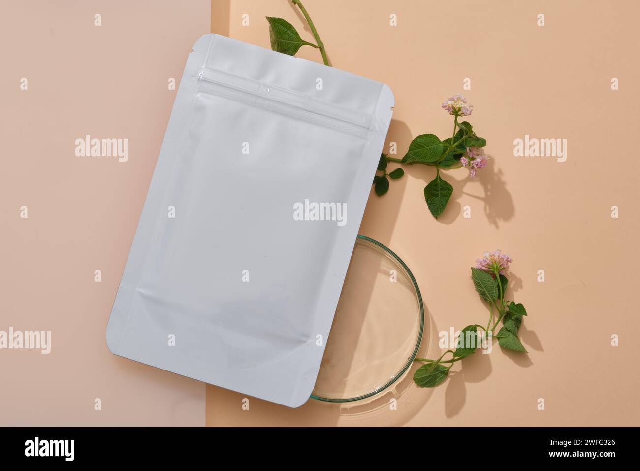 Feuille de masque facial sans étiquette décorée d'une boîte de Pétri en verre et de quelques fleurs de Lantana camara. Promotion de marque de beauté avec concept naturel Banque D'Images