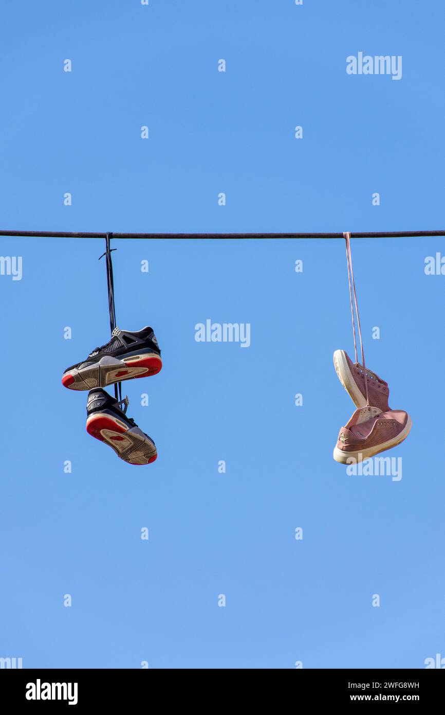 Vieilles baskets accrochées à un fil électrique contre un ciel bleu. Banque D'Images