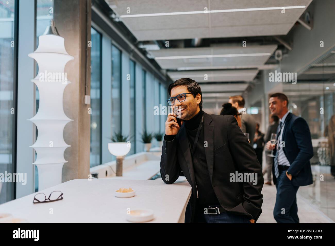 Souriant jeune homme d'affaires parlant sur le téléphone portable pendant la conférence Banque D'Images
