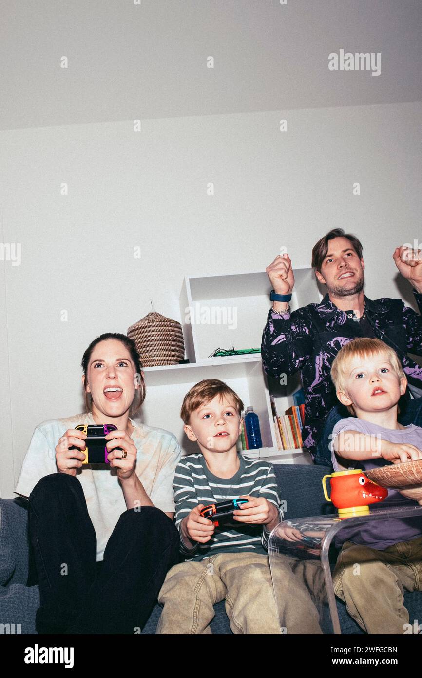 Famille heureuse appréciant tout en jouant au jeu vidéo à la maison Banque D'Images