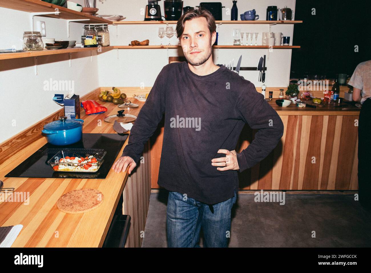 Portrait d'homme debout avec la main sur la hanche tout en préparant la nourriture dans la cuisine à la maison Banque D'Images