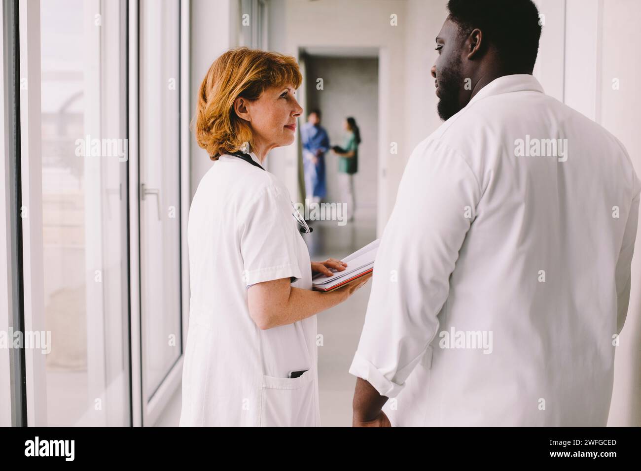 Médecin senior discutant avec un collègue masculin dans le couloir à l'hôpital Banque D'Images