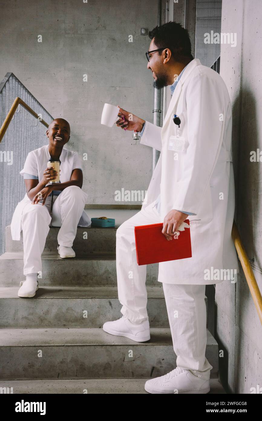 Heureux collègues médicaux parlant à l'escalier pendant la pause café Banque D'Images