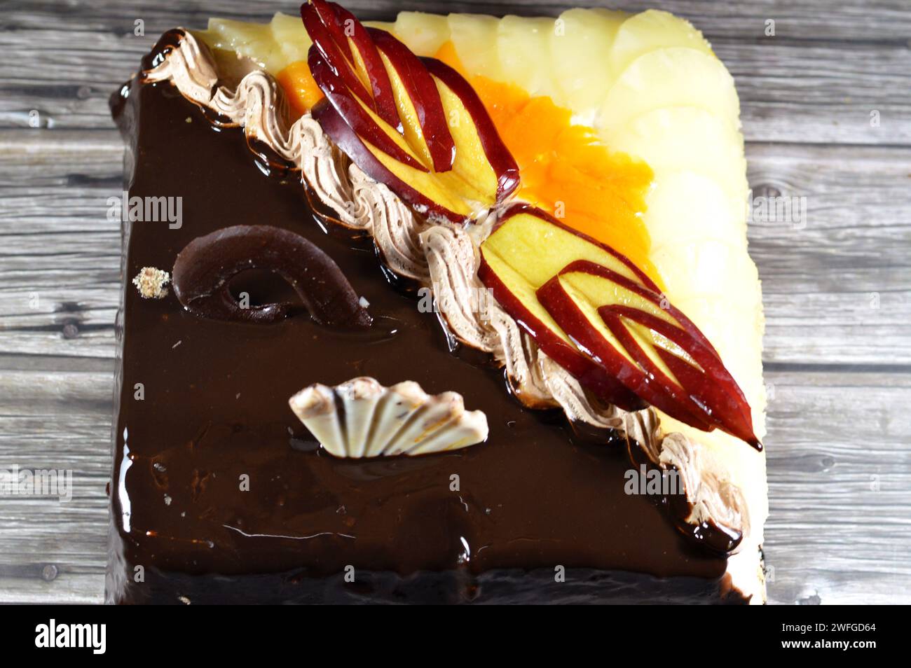 Gâteau d'anniversaire de deux moitiés différentes pièces gâteau crémeux spongieux pour les célébrations, chocolat noir, caramel, crème fouettée à la vanille, tranches d'ananas Banque D'Images