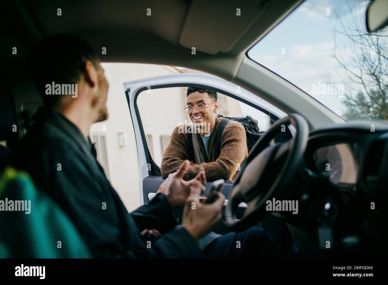 Homme souriant regardant un ami assis à l'intérieur du van Banque D'Images