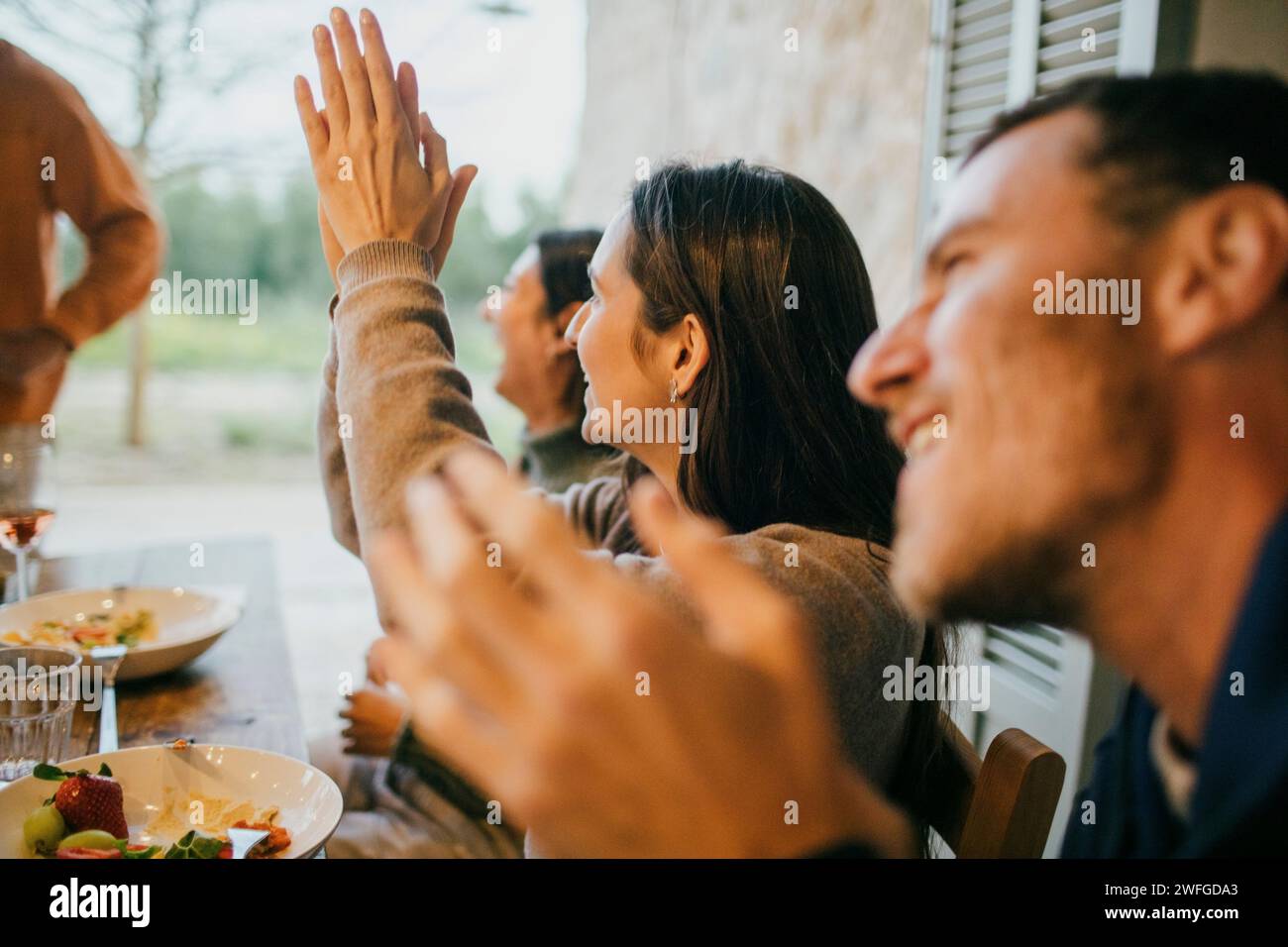 Heureux amis applaudissant pendant le dîner dans le patio Banque D'Images