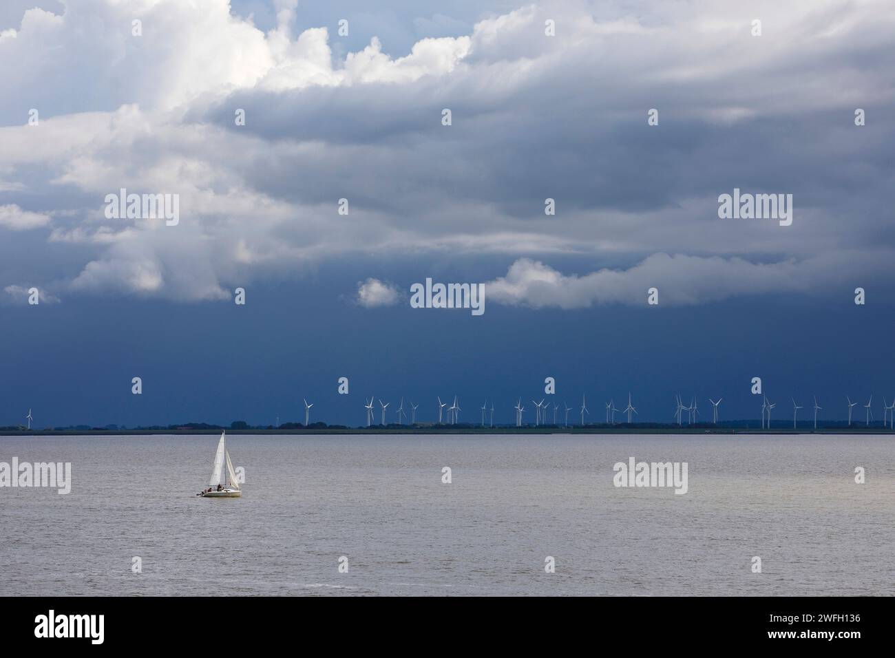 Bateau à voile sur la mer du Nord devant les éoliennes dans les marais, Allemagne, Basse-Saxe, Frise orientale, Norddeich Banque D'Images