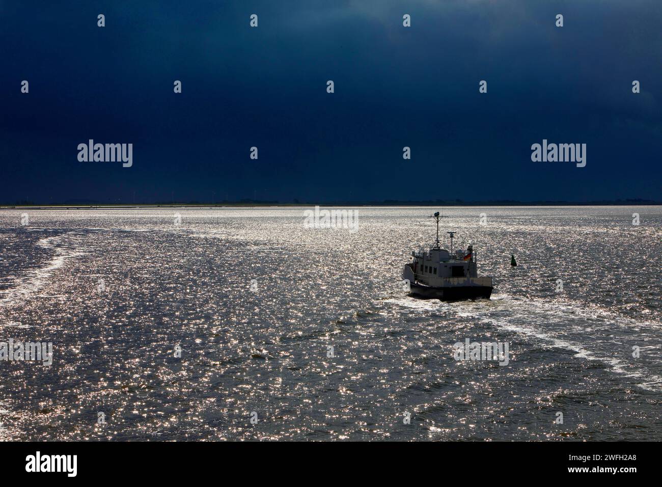 Bateau sur la mer du Nord rétro-éclairé avec un ciel dramatiquement sombre, Allemagne, Basse-Saxe, Frise orientale, Mer du Nord Banque D'Images