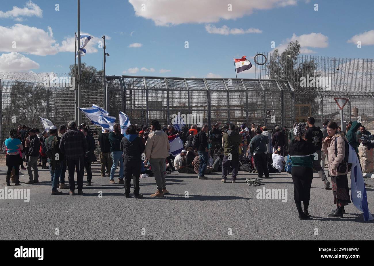 Les manifestants israéliens se rassemblent près de la barrière frontalière avec l'Egypte au point de passage de Nitzana et empêchent les camions humanitaires d'entrer en Israël pour inspection avant d'être envoyés à Rafah pour entrer dans Gaza, exigeant que l’aide humanitaire ne soit fournie qu’en échange de la libération des otages israéliens détenus à Gaza le 30 janvier 2024 à Nitzana, en Israël. Banque D'Images