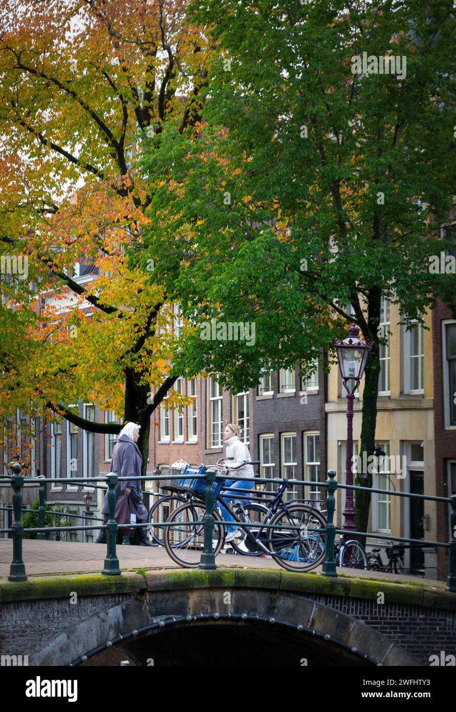 Amsterdam, pays-Bas–31 octobre 2023 : les gens marchent sur le pont sur le canal, les arbres colorés d'automne Banque D'Images