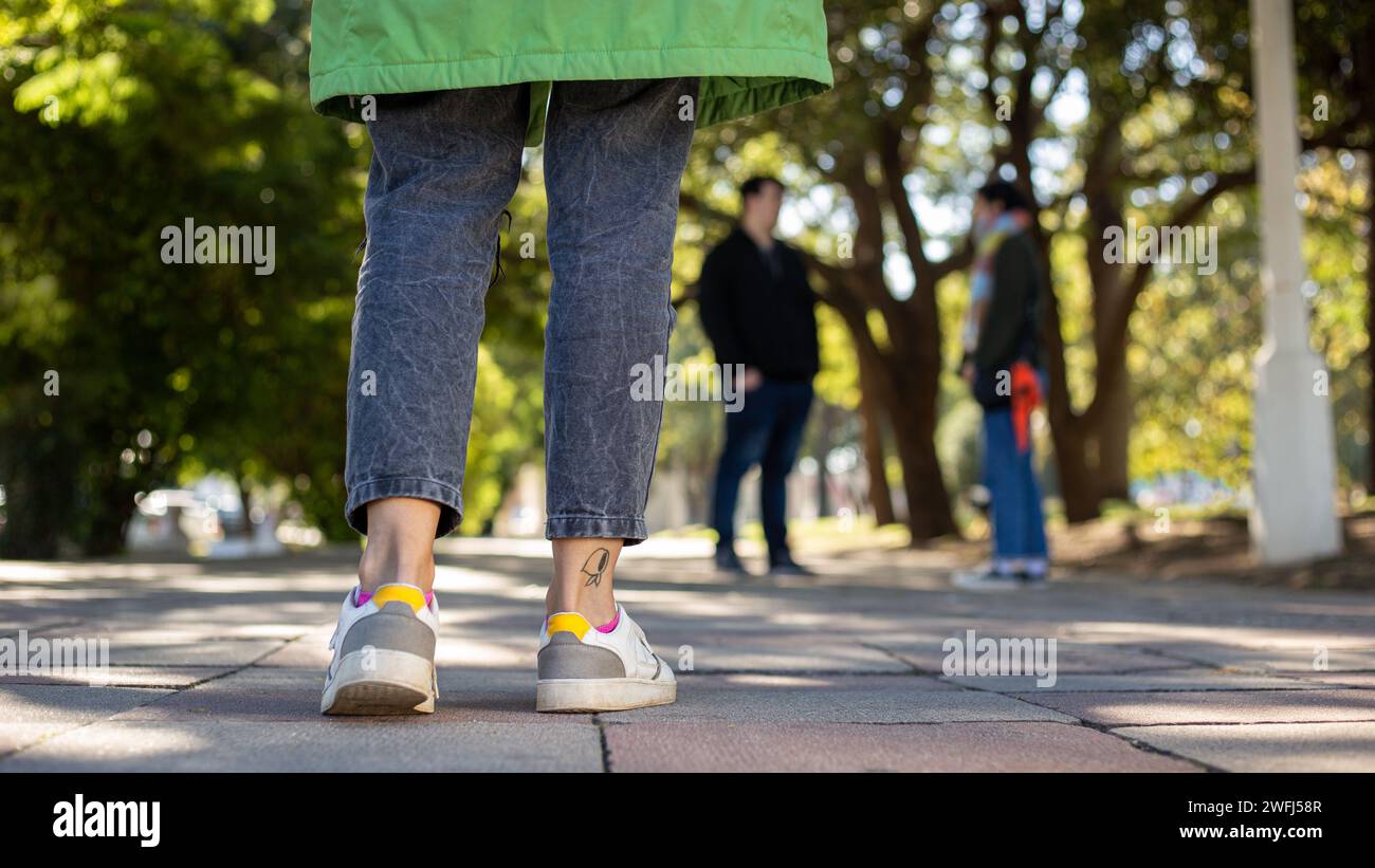 Les gens en chaussures Converse se promènent sur le trottoir, portant des sacs Banque D'Images