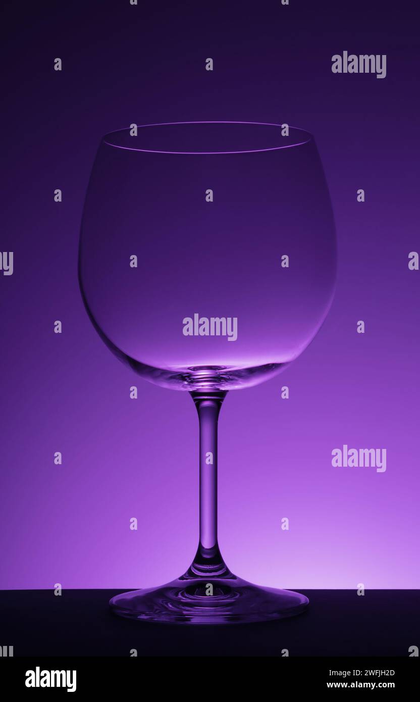 Verre à vin vide sur fond violet. Banque D'Images