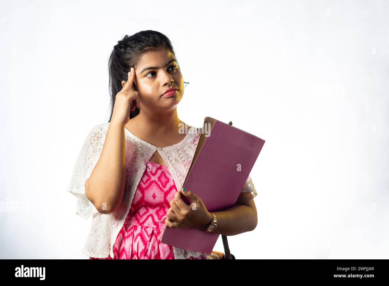 Une jolie jeune fille indienne pensant et regardant de côté sur fond blanc Banque D'Images