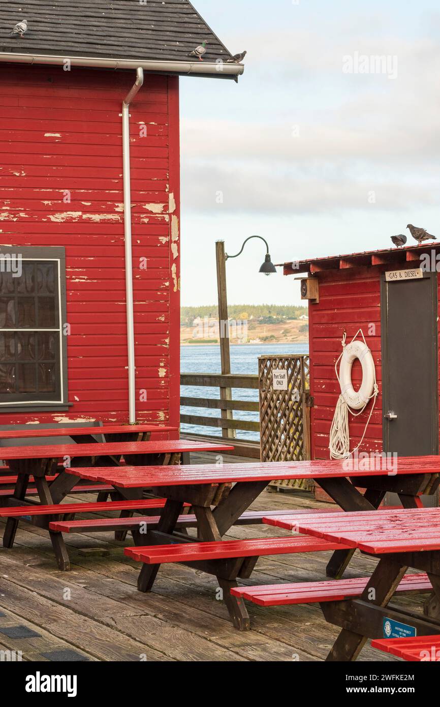 Des tables de pique-nique rouges vacantes sont alignées à l'extérieur du quai public historique de Coupeville, Whidbey Island, dans l'État de Washington. Banque D'Images