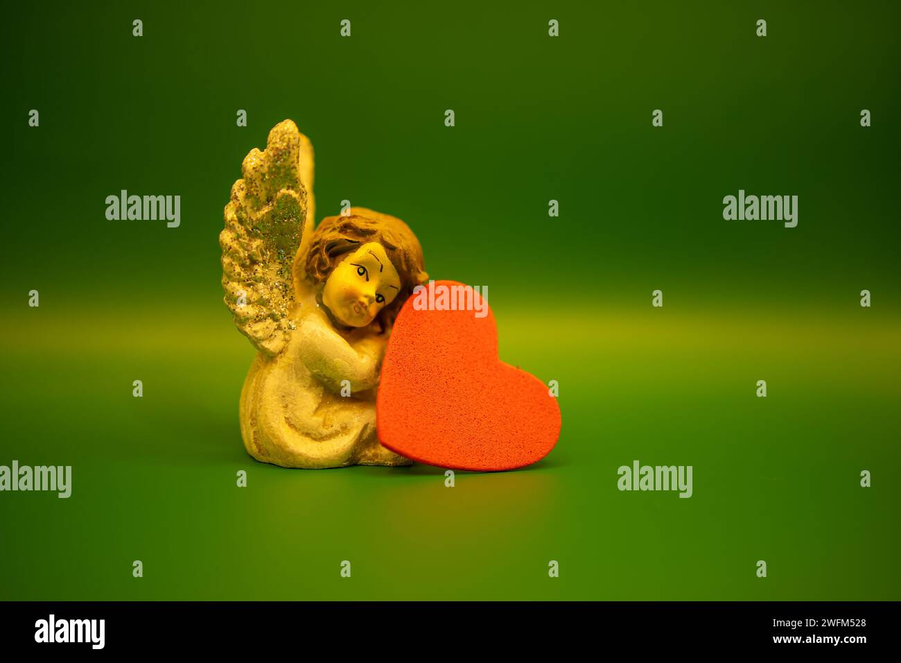 Un petit ange et un foyer sur fond vert. Saint-Valentin, 14 concept de février. Ornements d'ange de Noël. Angel et concept d'amour. Banque D'Images