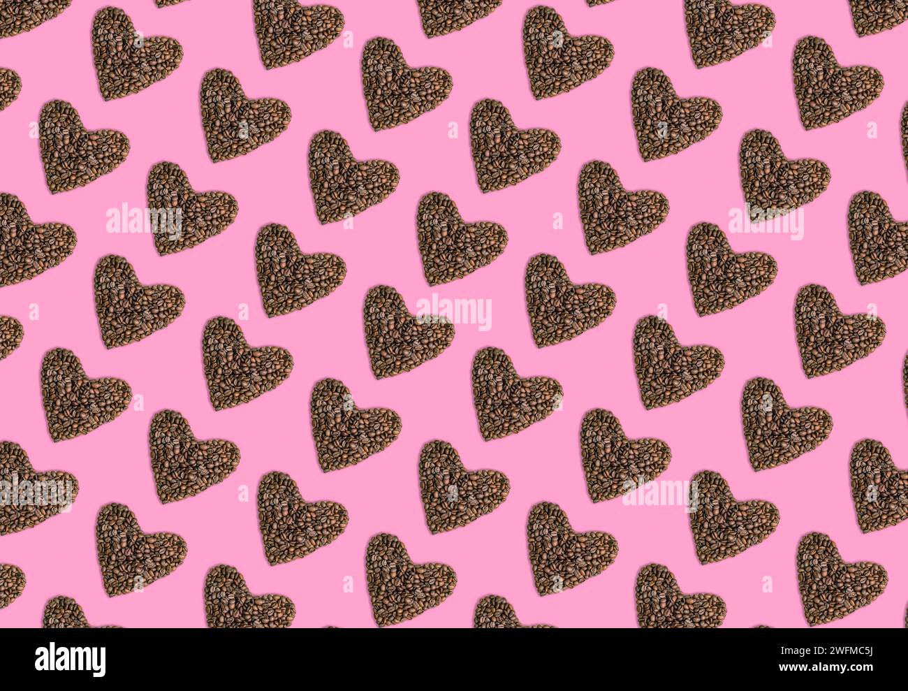 Motif de coeurs fabriqués à partir de grains de café sur fond rose. Concept de Saint Valentin. Banque D'Images