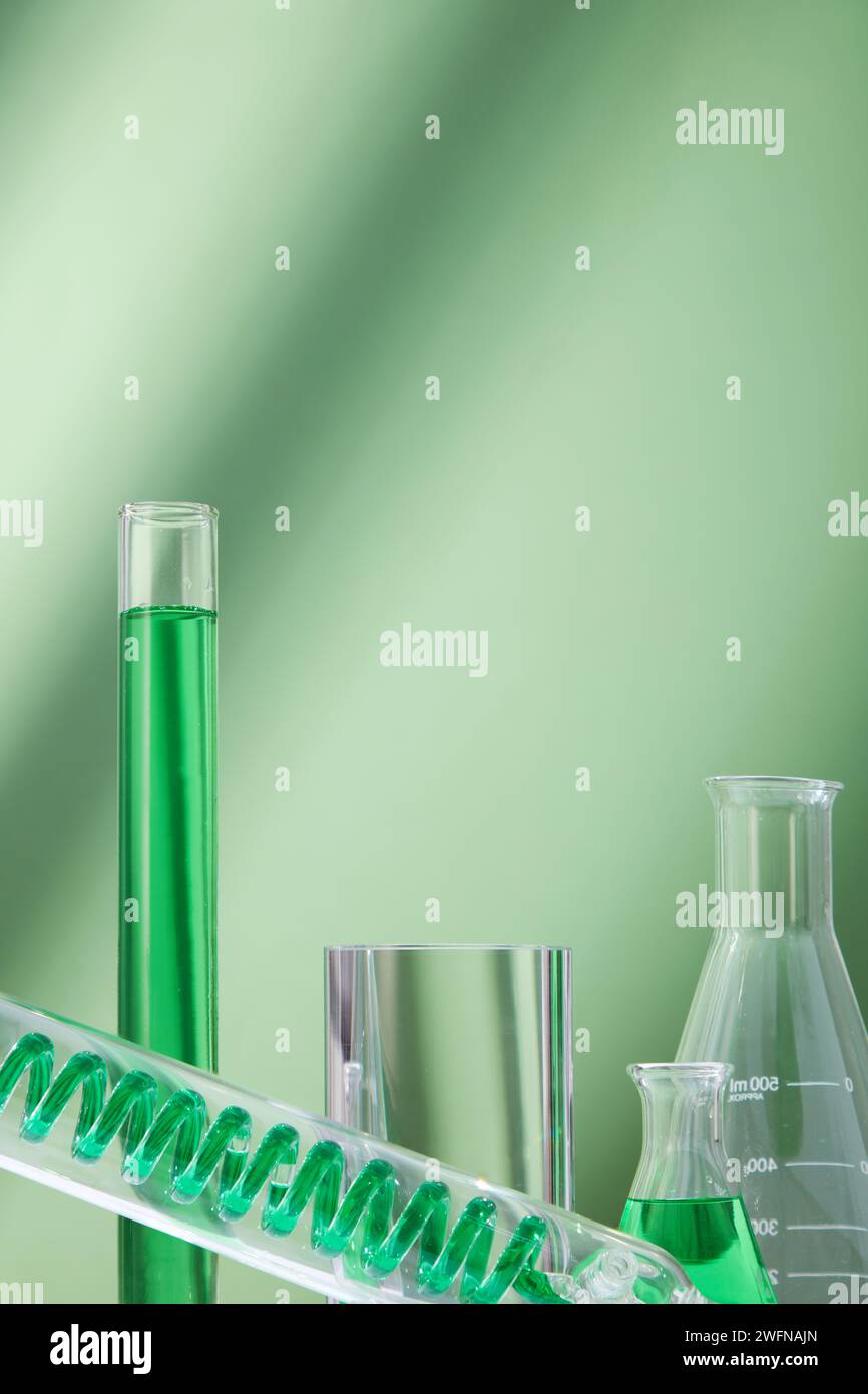 Vue rapprochée de la verrerie de laboratoire remplie d'eau verte affichée sur fond vert. Concept de recherche et développement en laboratoire scientifique Banque D'Images